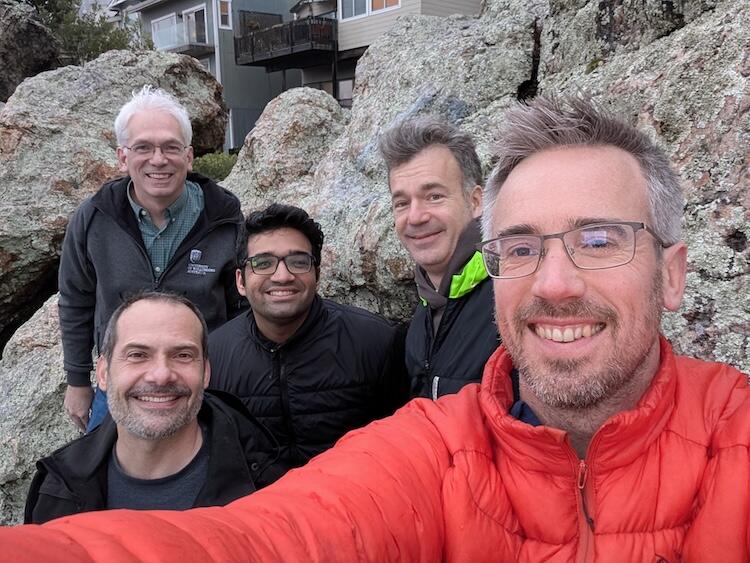 A group of 4 people pose outside near a large rock outcropping in Berkeley, CA
